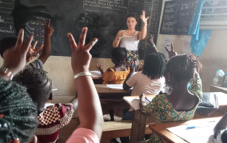 Une jeune bénévole en train de compter sur ses doigts face à une classe de jeunes filles.