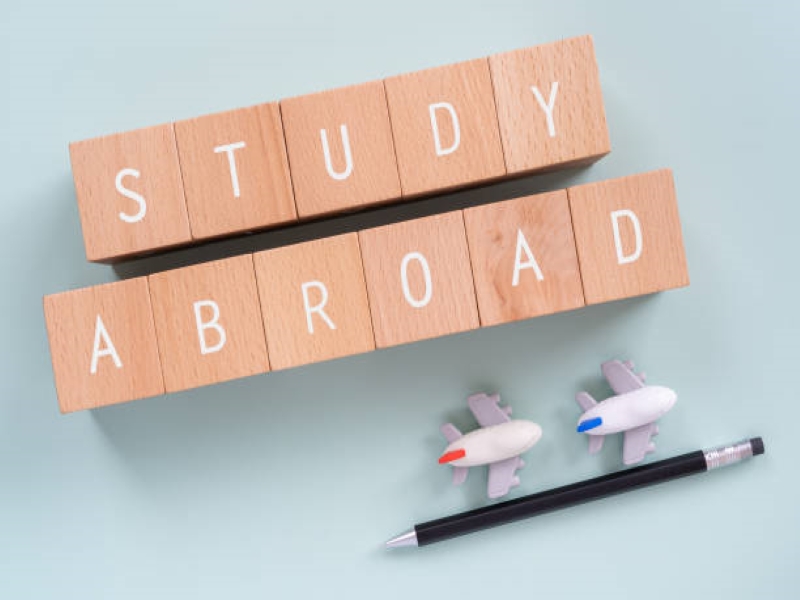 petits cube en bois avec inscrit dessus "study abroad" avec deux petits avions et un crayon