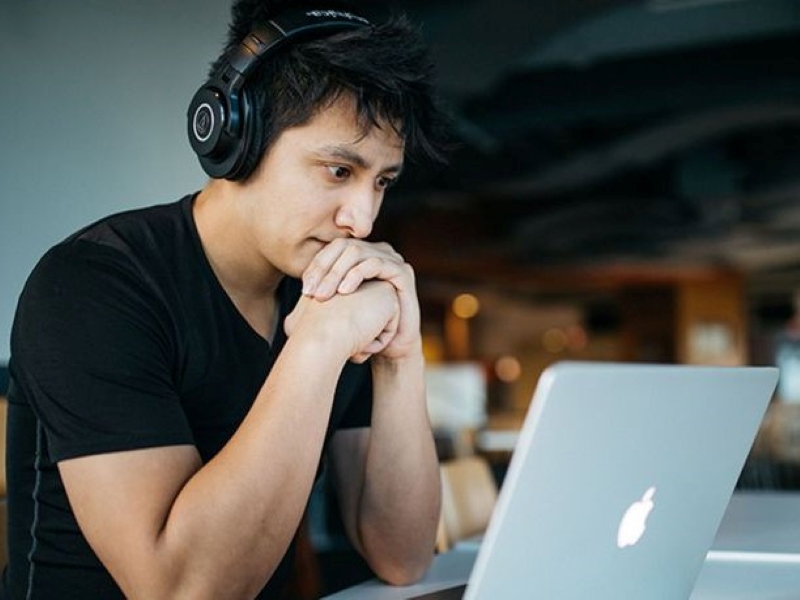 Un jeune homme est face à son ordinateur en train de réfléchir