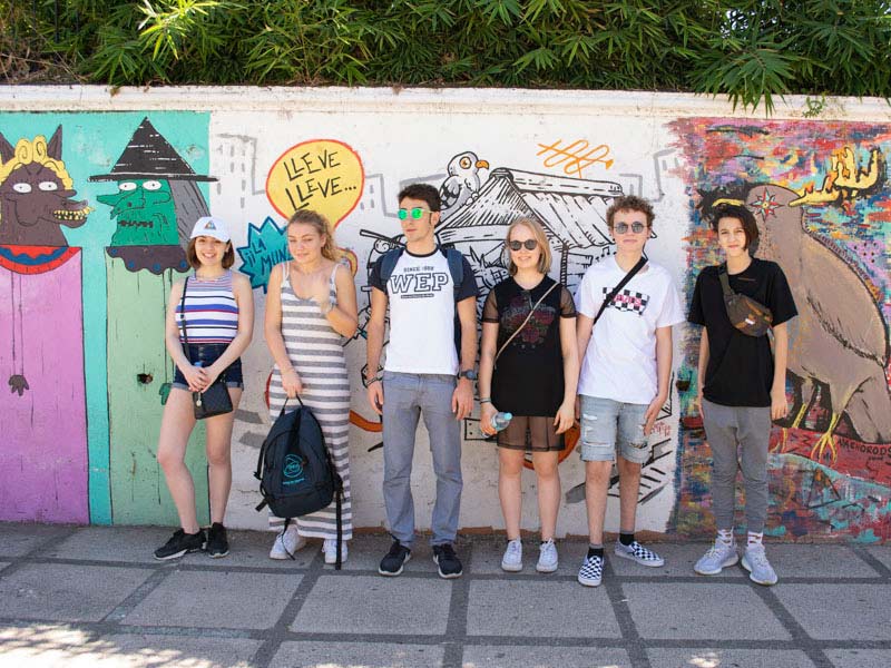 Six jeunes devant un mur avec des peintures
