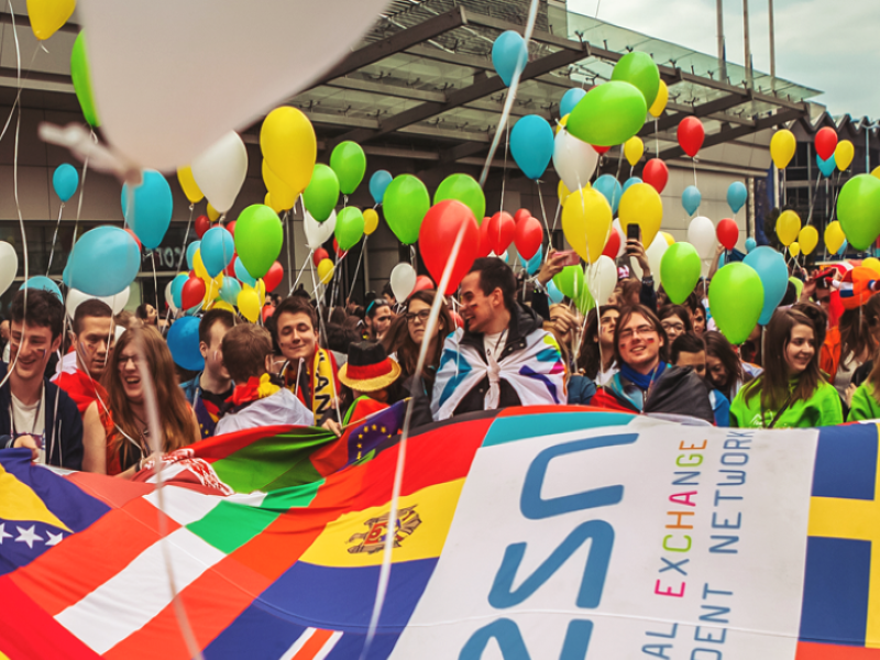 Un groupe d'étudiants internationaux avec des ballons et des drapeaux.